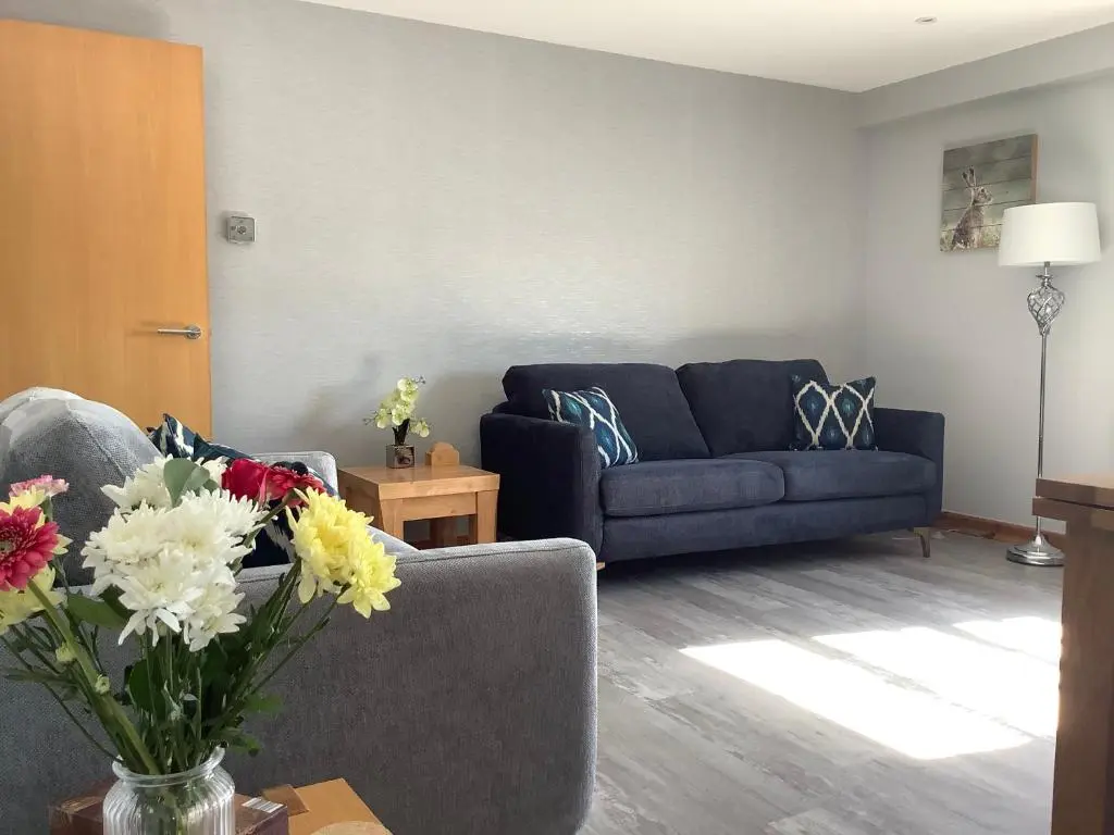 a living room with a couch and flowers on a table at 37 Farraline Court, City Centre apartment in Inverness