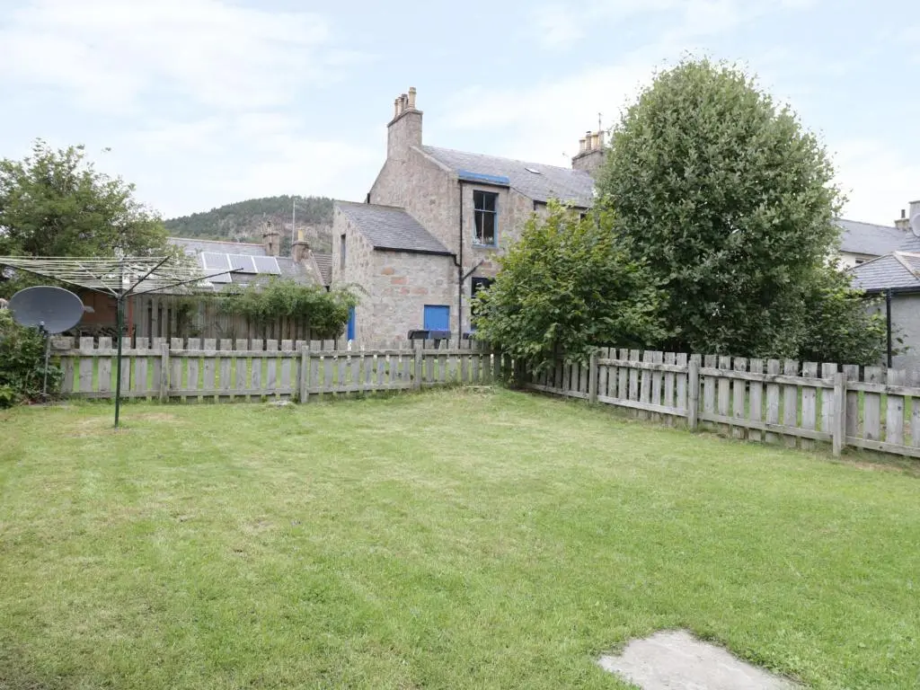 a yard with a wooden fence and a house at Westwood in Ballater