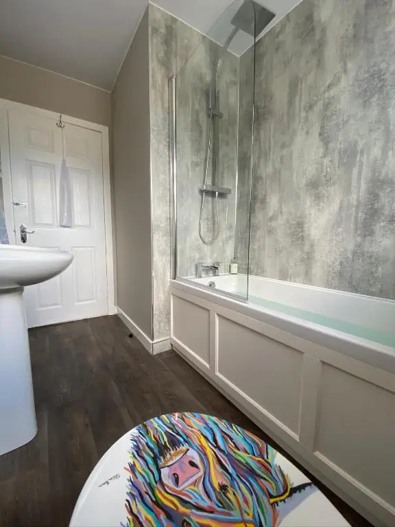 a bathroom with a tub and a shower and a rug at Wells Street Cottages No 26 By The River Ness in Inverness