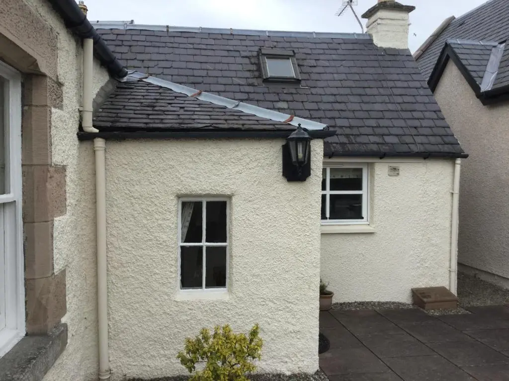 a white house with a black roof at Three-Bedroom Old Cottage Free Parking in Inverness