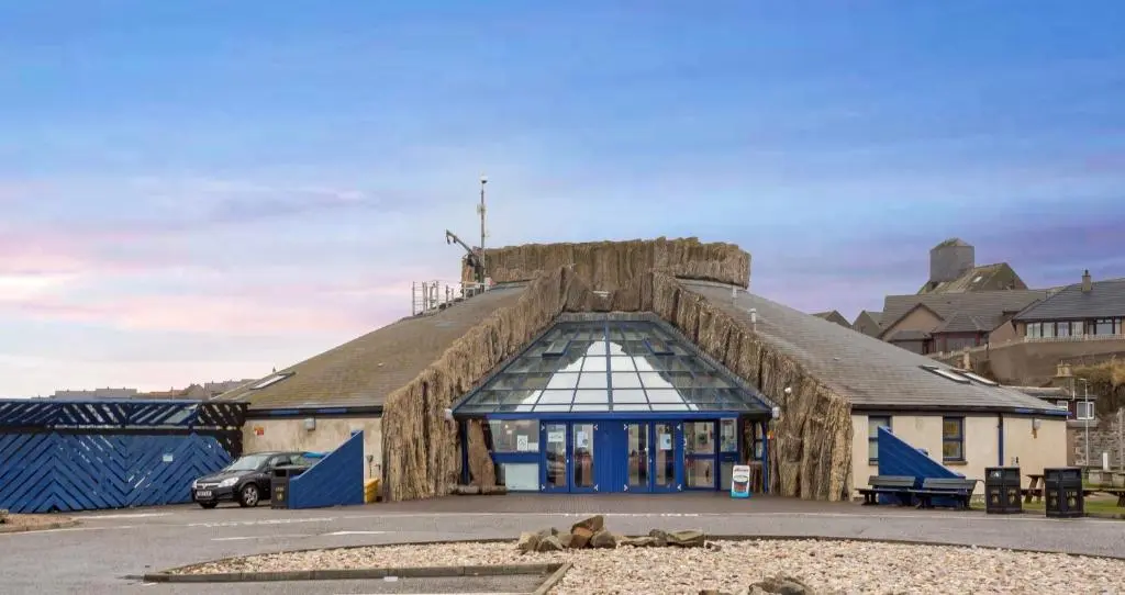 a large building with a large roof with blue doors at Seaesta Apartments in Macduff