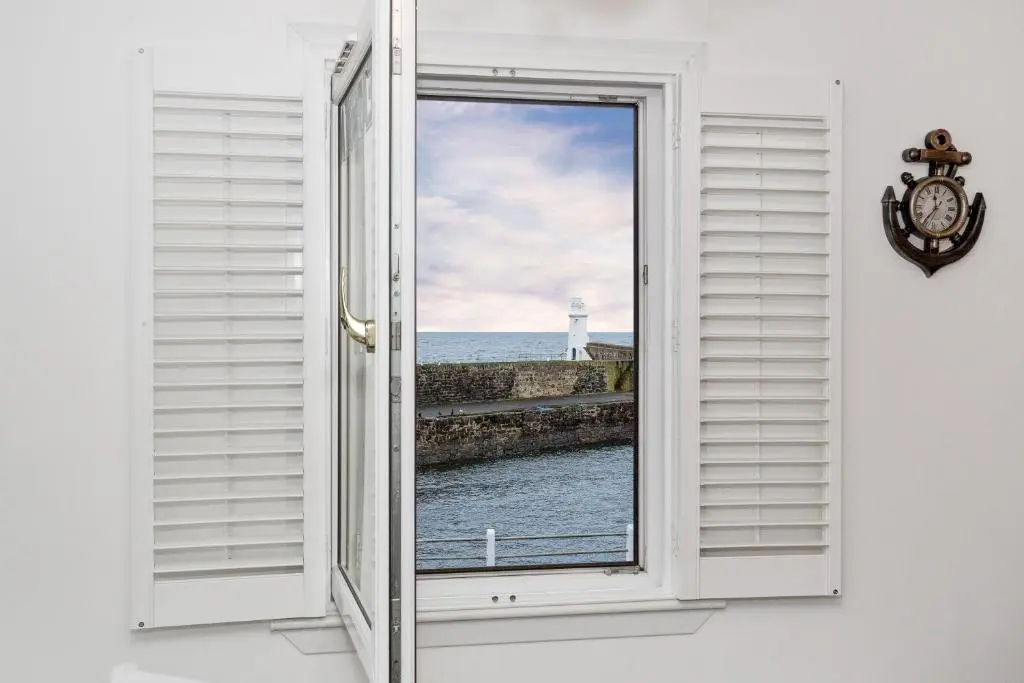 an open window with a view of a lighthouse at Seaesta Apartments in Macduff