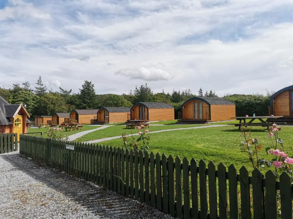 a fence in front of a yard with wooden buildings at Greencraig Pods in Buckie