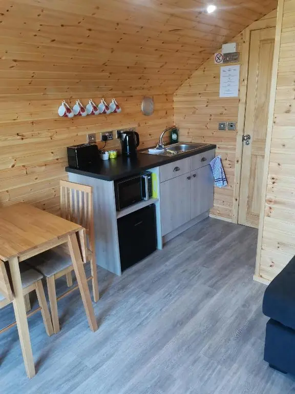 a kitchen with a stove and a sink and a table at Greencraig Pods in Buckie