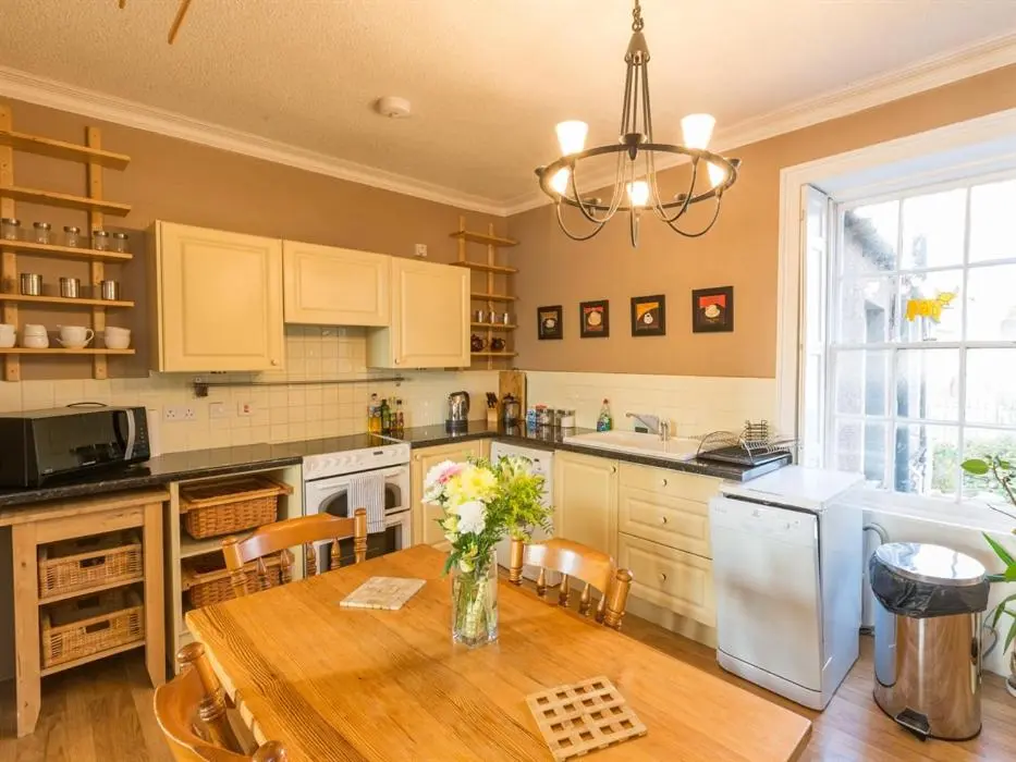 a kitchen with a table with a vase of flowers on it at River Cottage in Inverness