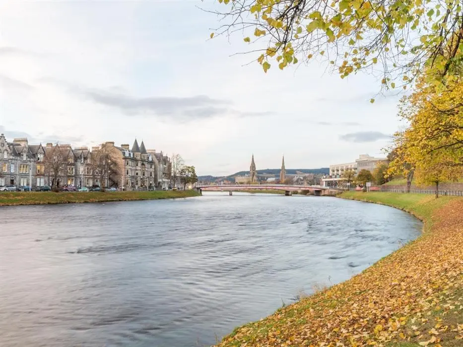 a view of a river in a city with buildings at River Cottage in Inverness