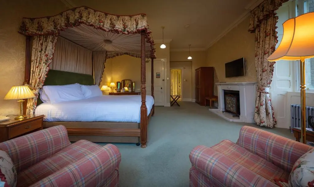 a bedroom with a canopy bed and a fireplace at Glengarry Castle Hotel in Invergarry