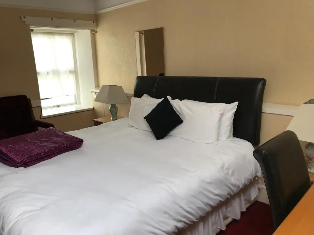 a bedroom with a white bed with a black headboard at The Old Coach House in Buckie