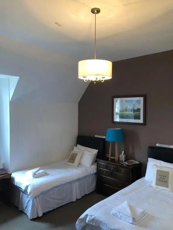 a hotel room with two beds and a chandelier at Westerlea Hotel Nairn in Nairn