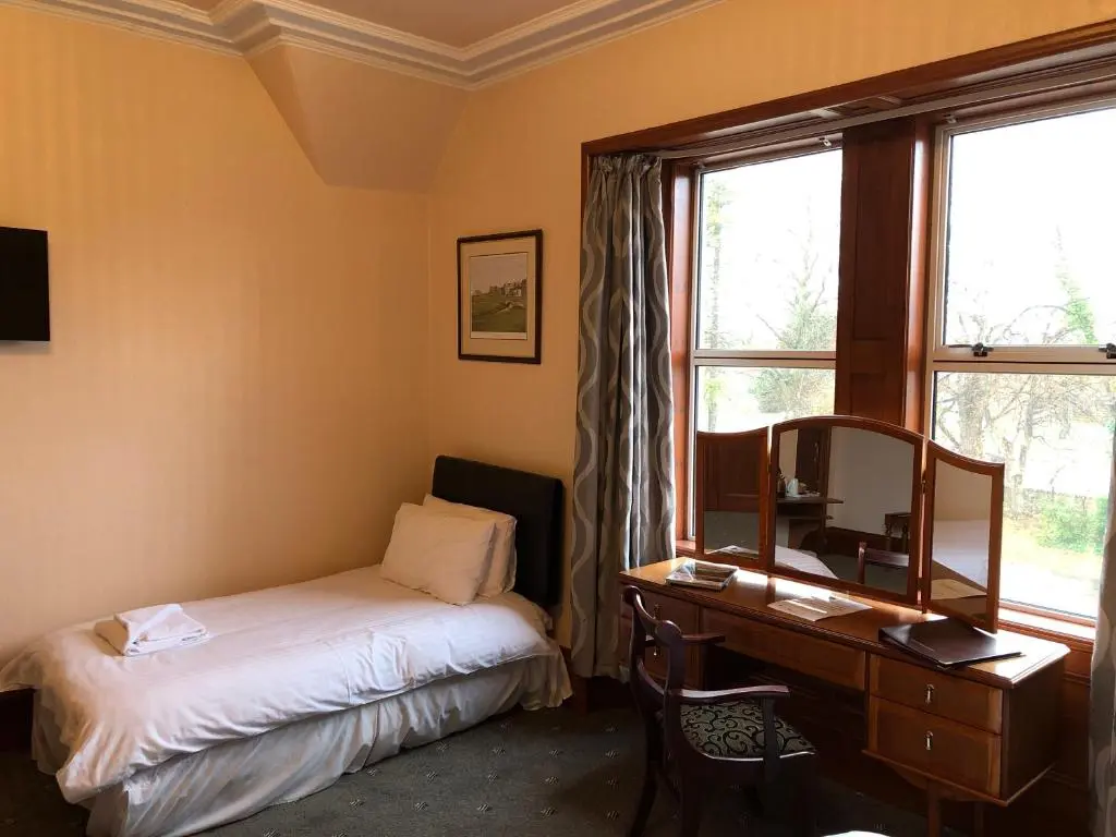 a bedroom with a desk and a bed and a mirror at Westerlea Hotel Nairn in Nairn