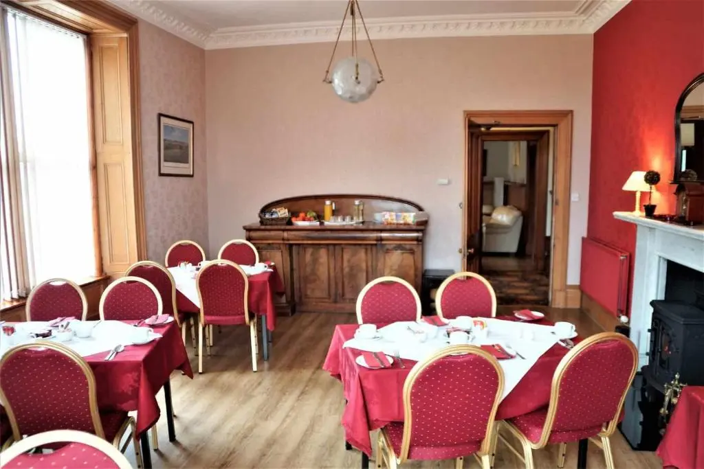 a dining room with tables and chairs and a fireplace at Westerlea Hotel Nairn in Nairn