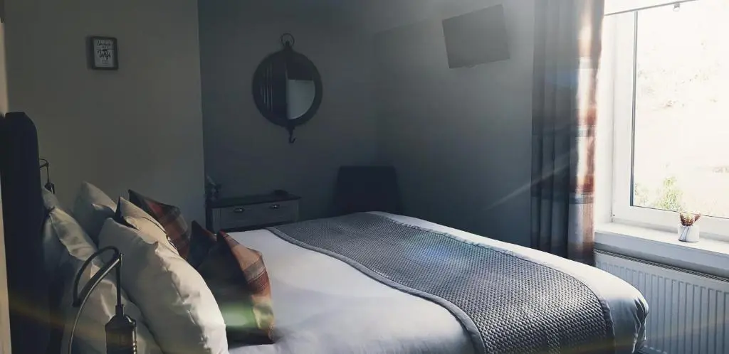 a bedroom with a bed with a mirror and a window at Airanloch Bed & Breakfast,Loch Ness, Adult Only in Lochend