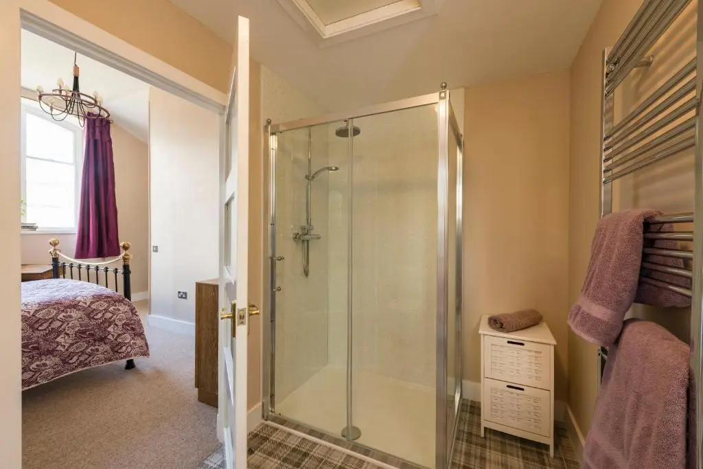 a bathroom with a shower with a glass door at Evelix, The Old School House in Muir of Ord