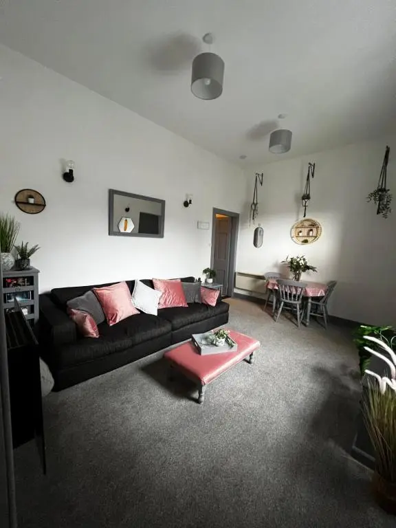 a living room with a black couch and a table at The Sheriffs Lodge in Dingwall