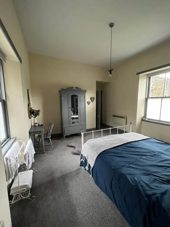 a bedroom with a bed and a dresser and windows at The Sheriffs Lodge in Dingwall