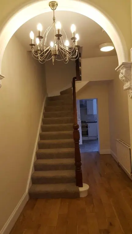 a hallway with a staircase with a chandelier at SPRINGBANK Holiday Home in Inverness