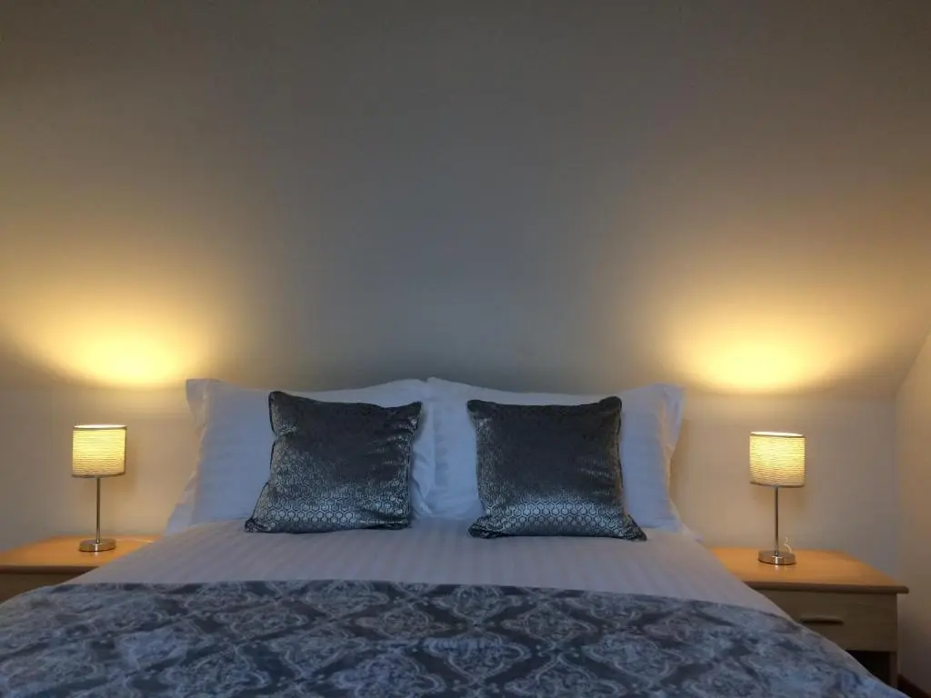 a bedroom with a bed with two lamps on two tables at LAIRDS COTTAGE in Stuartfield