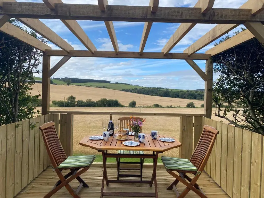 a wooden table and chairs on a wooden deck at LAIRDS COTTAGE in Stuartfield