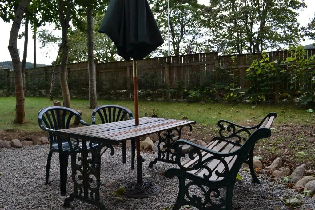 a wooden table with four chairs and an umbrella at Loch Ness Studio Blairbeg in Drumnadrochit