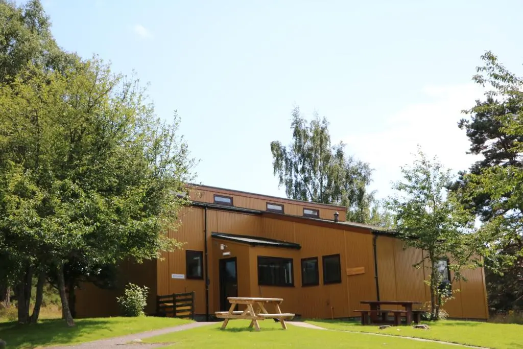 a building with a picnic table in front of it at Lagganlia Lodges and Camping Pods in Kincraig