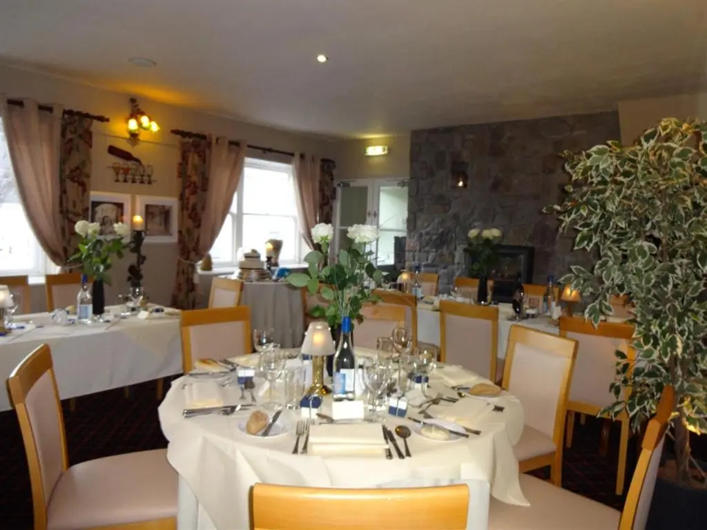 a dining room with white tables and chairs at The Commercial Hotel in Tarland