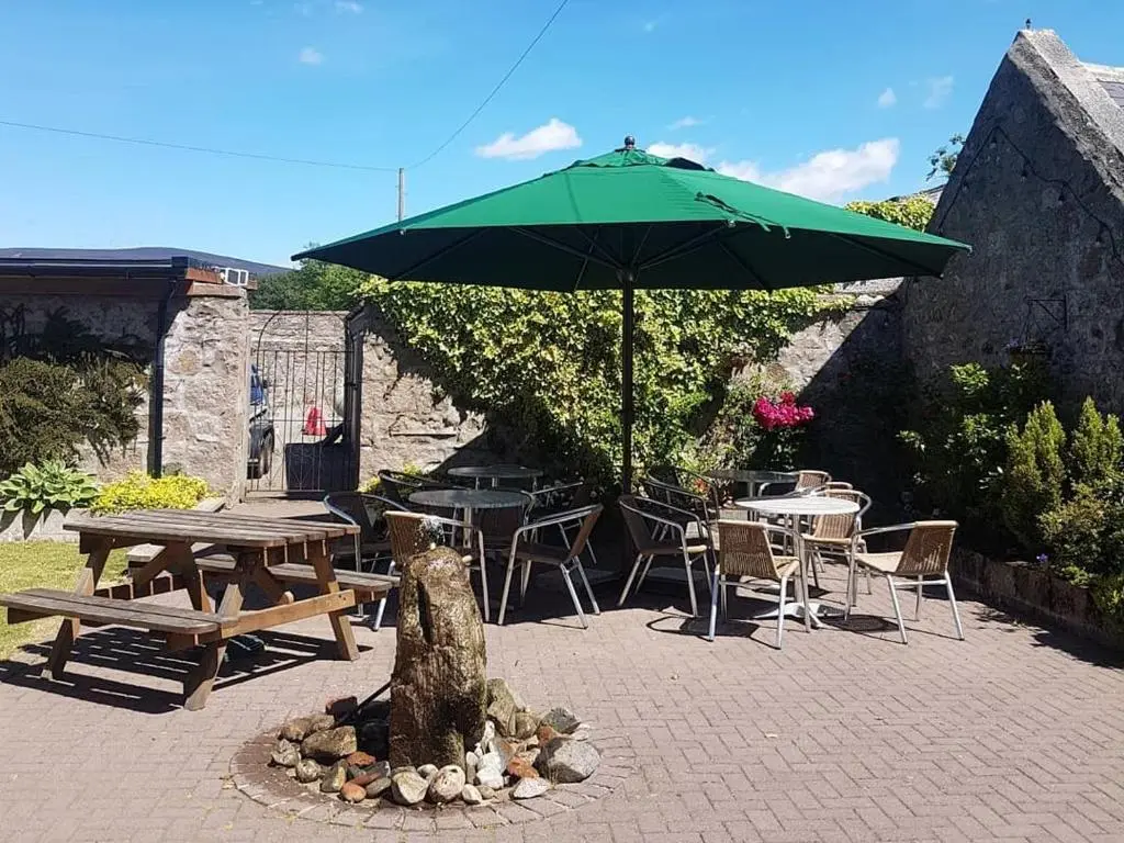 a patio with a picnic table and an umbrella at The Commercial Hotel in Tarland