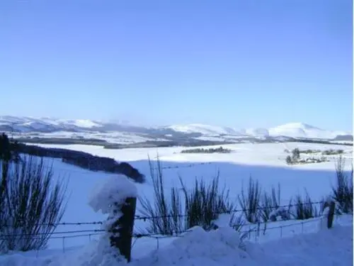 a snow covered field with a body of water at The Commercial Hotel in Tarland