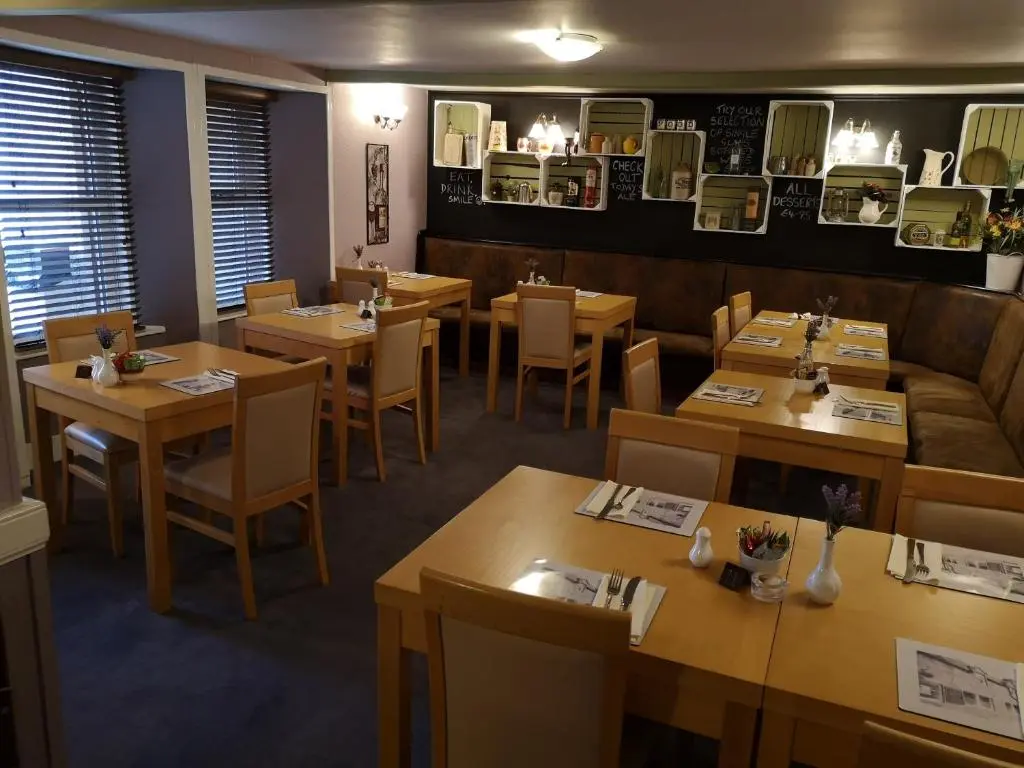 a restaurant with wooden tables and chairs and a couch at The Commercial Hotel in Tarland