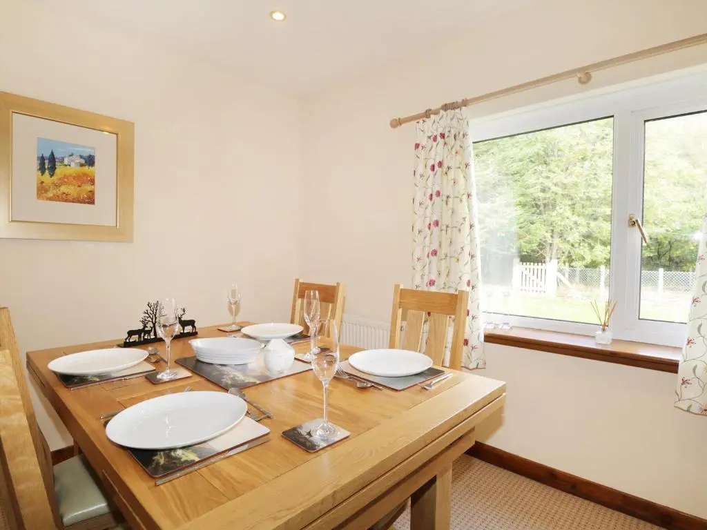 a dining room with a wooden table and a window at St Aethans in Inveran