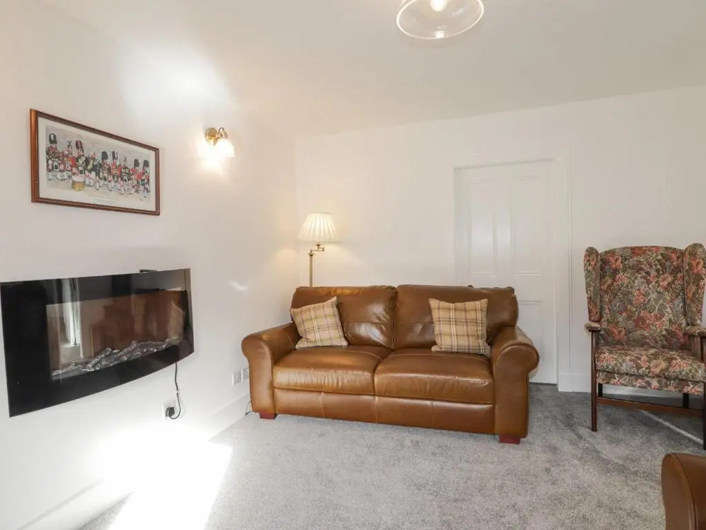a living room with a brown leather couch and a chair at 19 Reidhaven Street in Banff