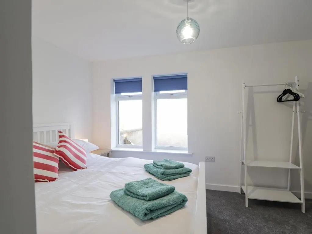 a white bed with three green towels on it at 19 Reidhaven Street in Banff