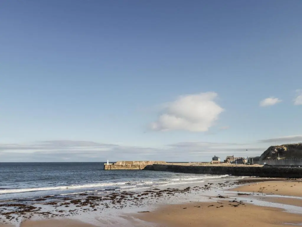 a beach with a pier and the ocean at 83 Seatown in Buckie