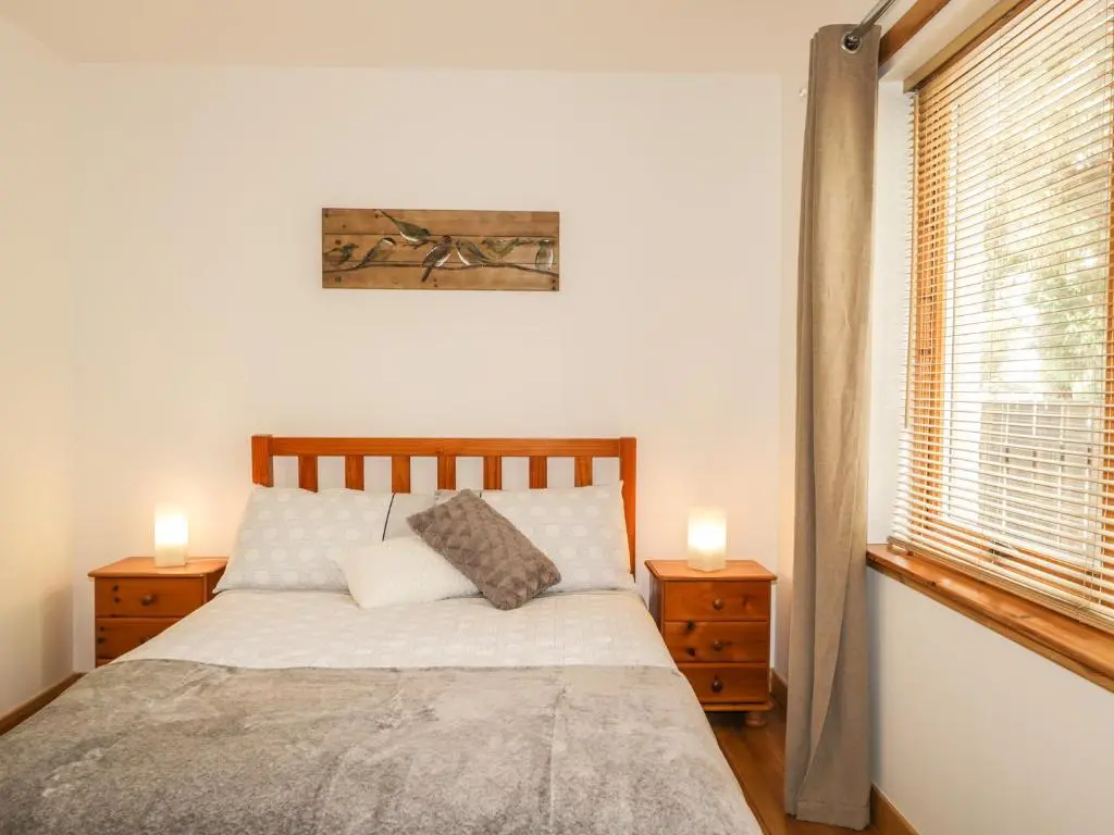 a bedroom with a bed with two night stands and a window at Dolce Casa in Grantown on Spey