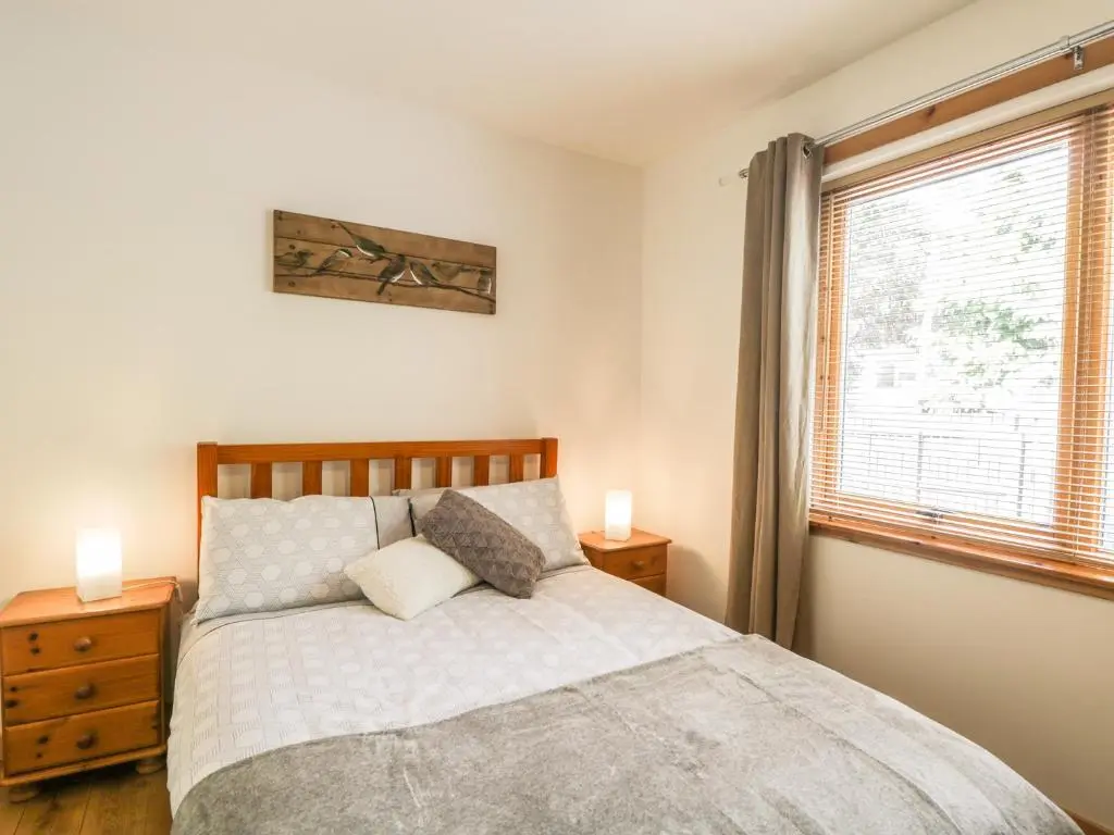 a bedroom with a bed with two night stands and a window at Dolce Casa in Grantown on Spey
