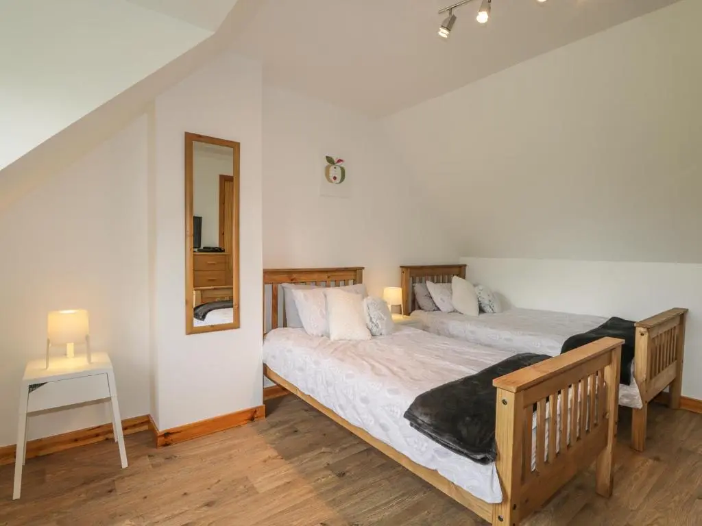 two beds in a room with two lamps and a mirror at Dolce Casa in Grantown on Spey