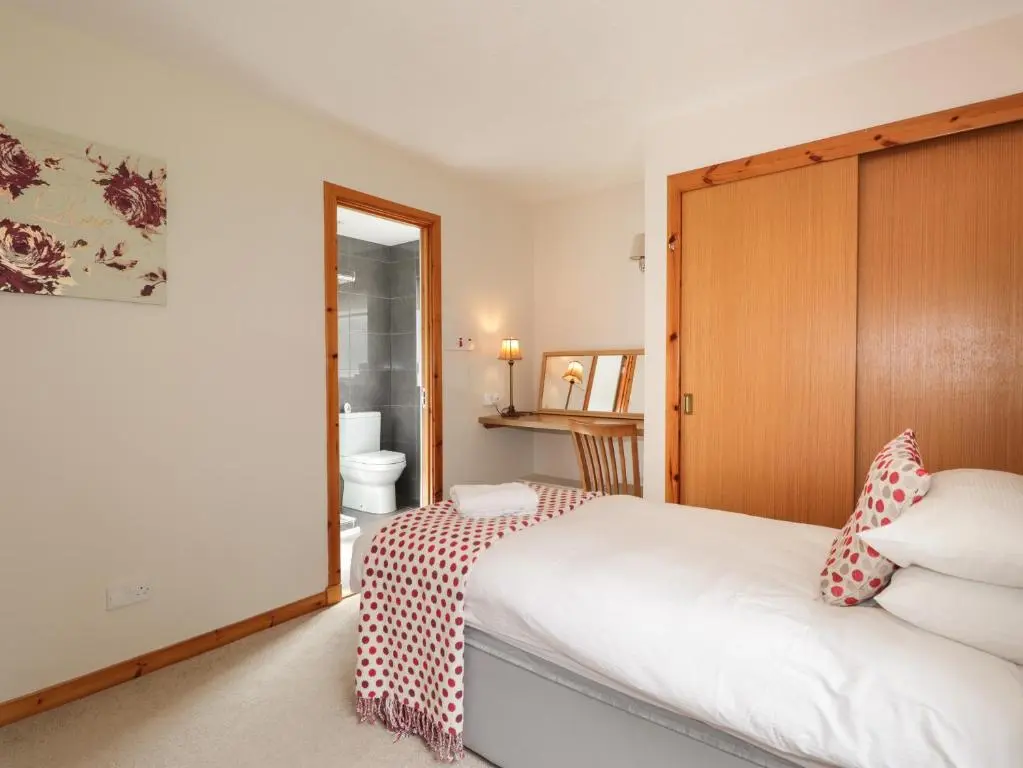 a bedroom with a bed with a red and white blanket at Millview in Boat of Garten
