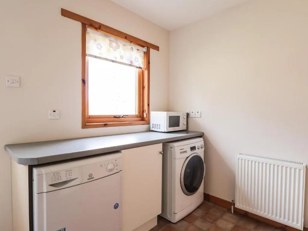a laundry room with a washing machine and a window at Millview in Boat of Garten