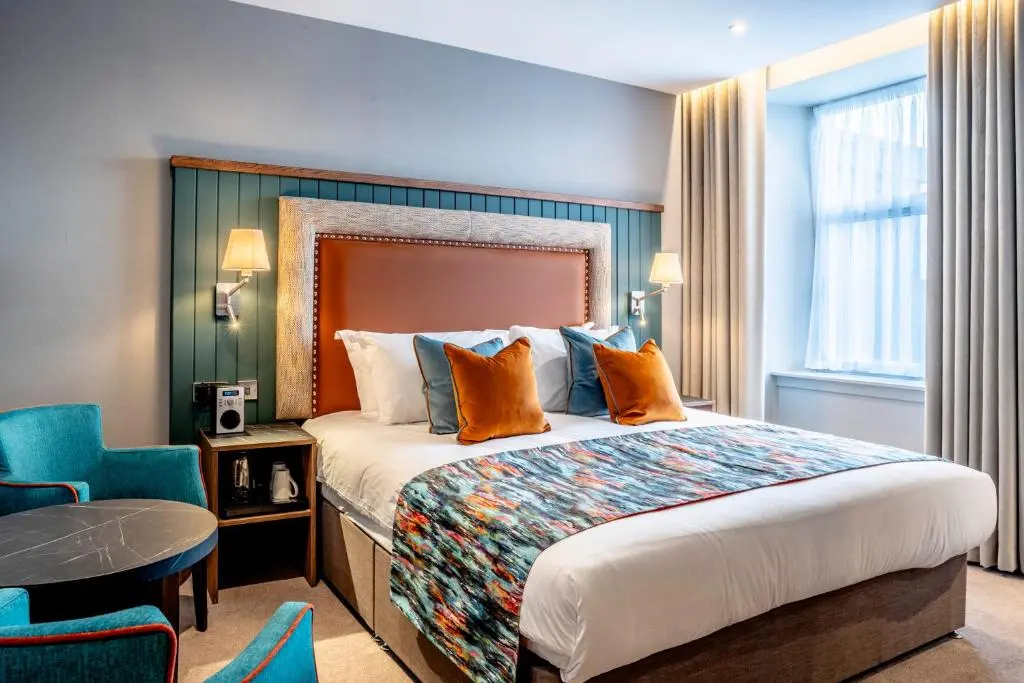 a hotel room with a large bed and a table at Star Hotel Kingussie in Kingussie