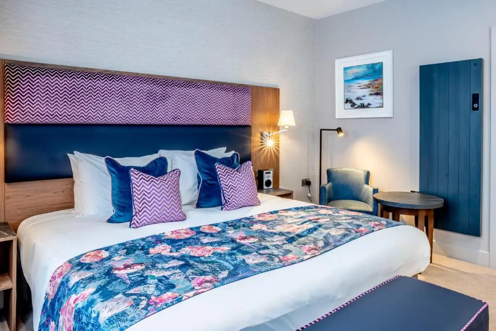 a hotel room with a large bed with purple and blue pillows at Star Hotel Kingussie in Kingussie