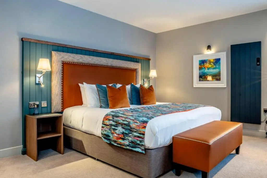 a hotel room with a large bed with orange and blue pillows at Star Hotel Kingussie in Kingussie