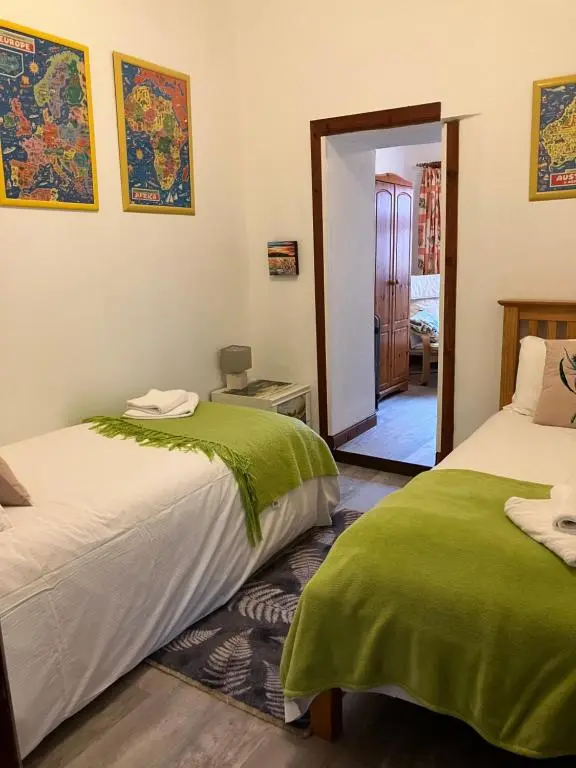 a bedroom with two beds and a doorway to a room at Islay Cottage, Meadowside, Kincraig, near Kingussie in Kincraig