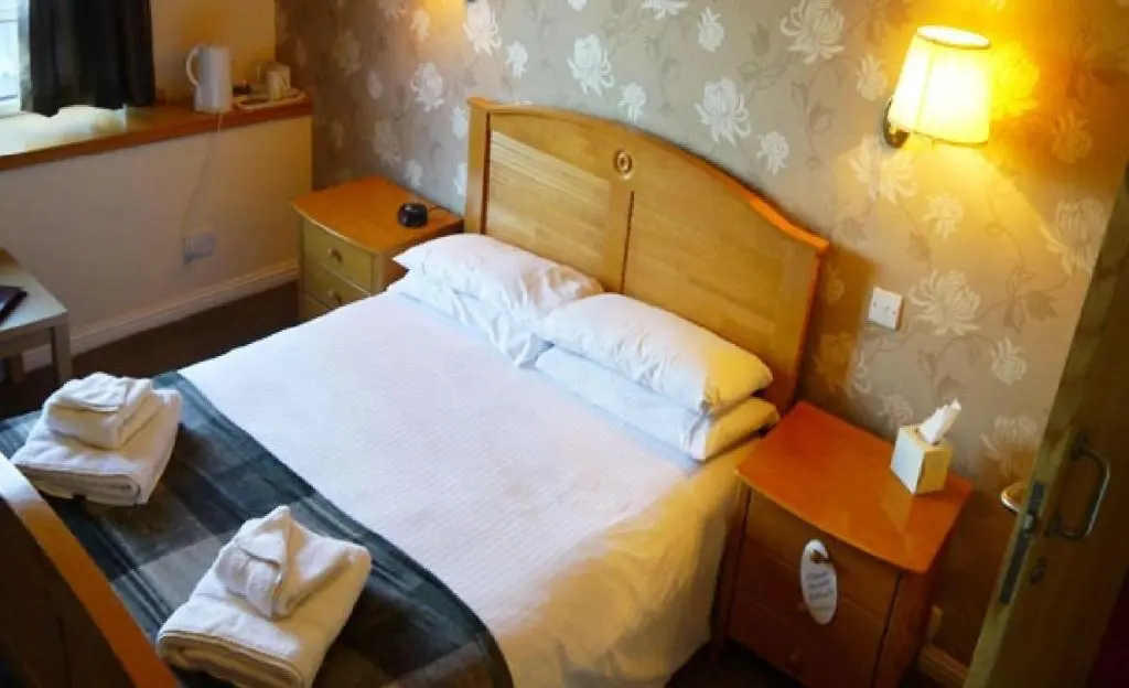a bedroom with a bed with white sheets and pillows at Ban Car Hotel in Cairness