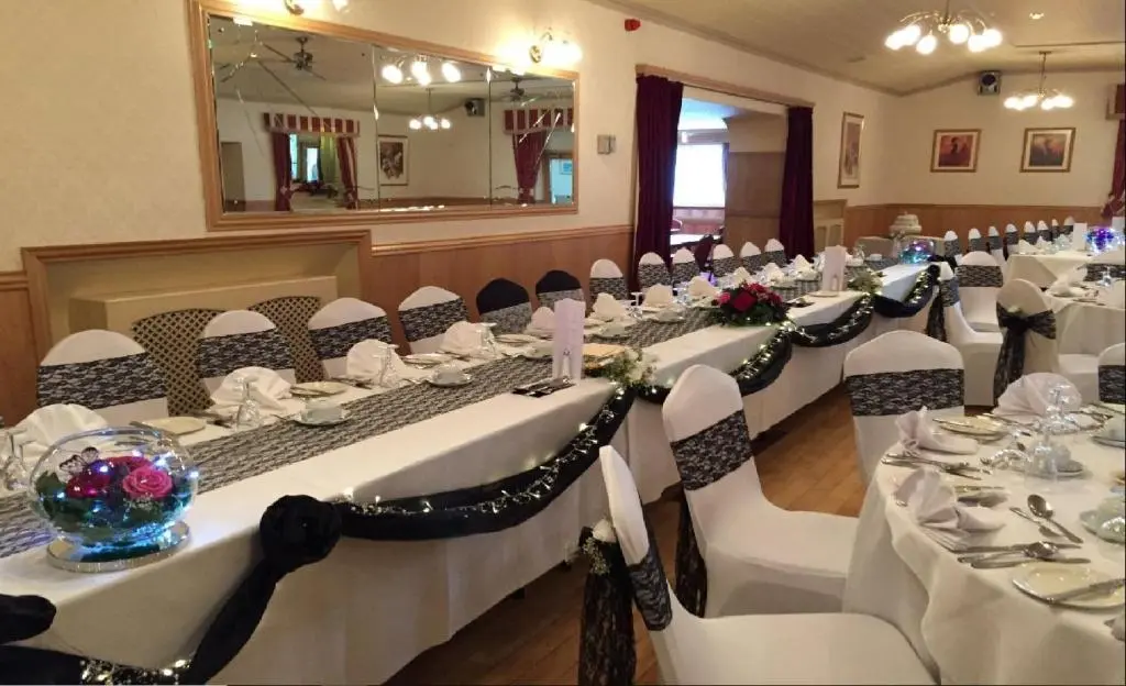 a room with white tables and chairs and a mirror at Ban Car Hotel in Cairness