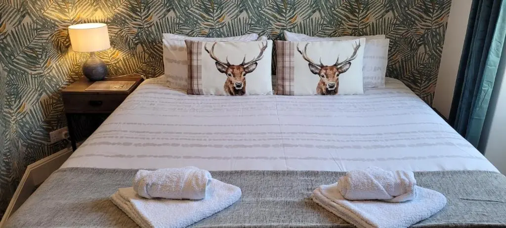 a bed with two towels and two deer heads on it at CHARMING VICTORIAN APARTMENT, close to centre in Inverness