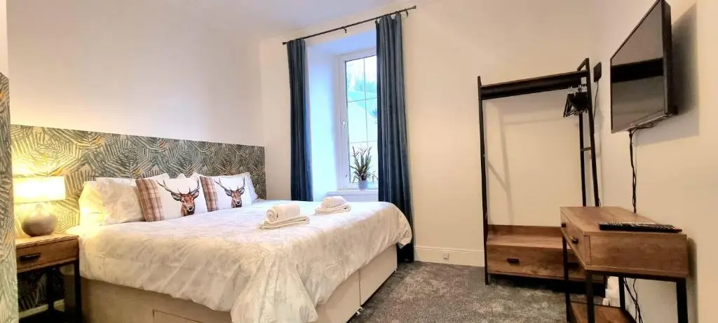 a bedroom with a bed with a television and a mirror at CHARMING VICTORIAN APARTMENT, close to centre in Inverness