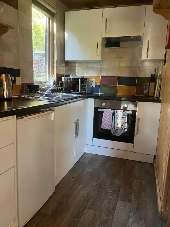 a kitchen with white cabinets and a stove top oven at Pine Marten Bar Glenmore Treehouse in Aviemore
