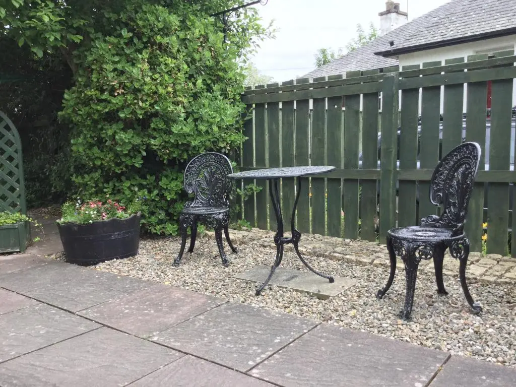 two chairs and a table in a yard with a fence at New Cottage 3 Bedroom Free Parking in Inverness