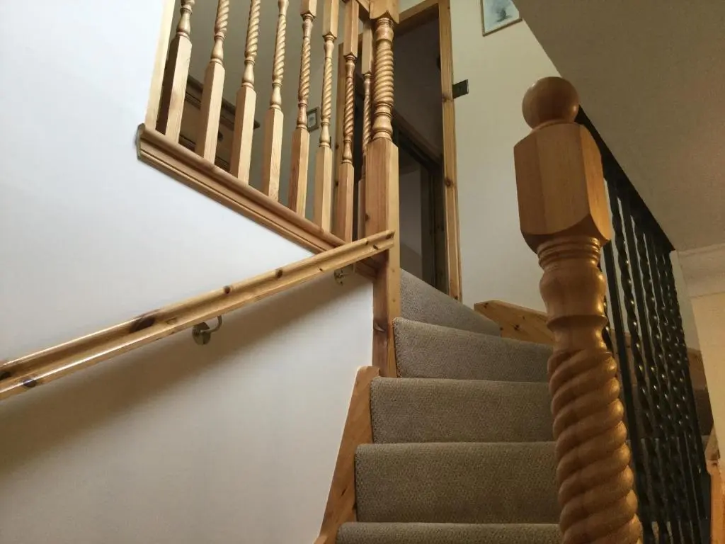 a stairway with a wooden rail and a stair case at New Cottage 3 Bedroom Free Parking in Inverness