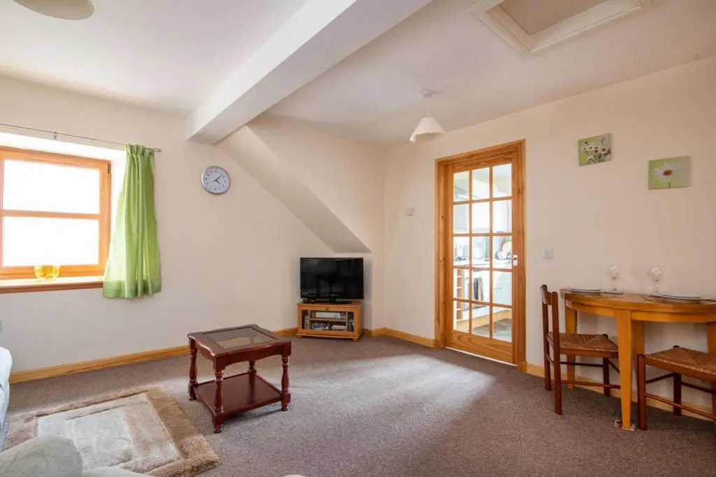 a living room with a table and a tv and a desk at Innes Street Apartments in Inverness