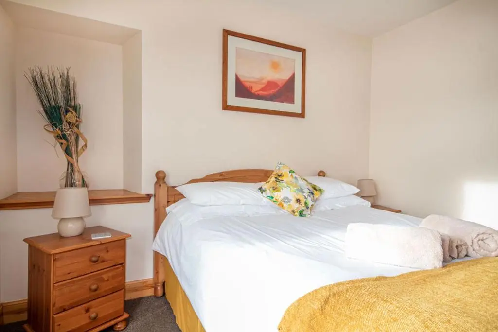 a bedroom with a bed and a dresser with a lamp at Innes Street Apartments in Inverness